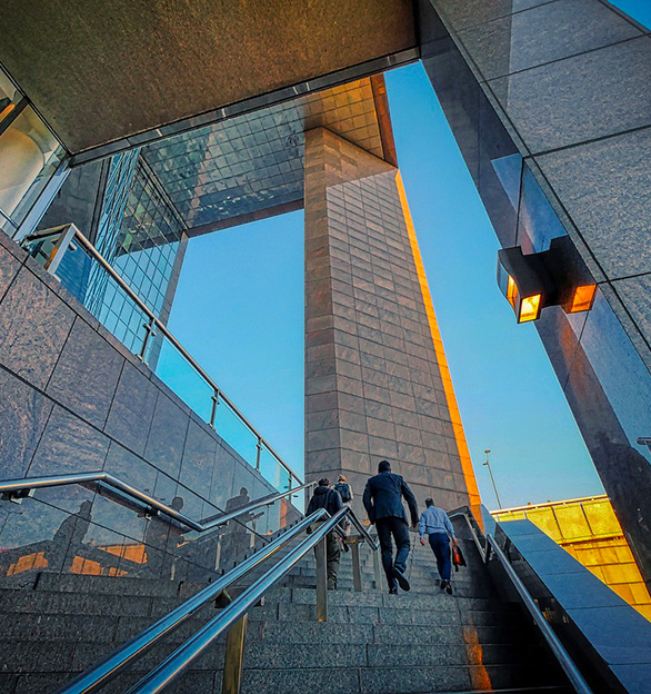 The image shows a staircase of a commercial building with a team of four people heading toward the entrance.